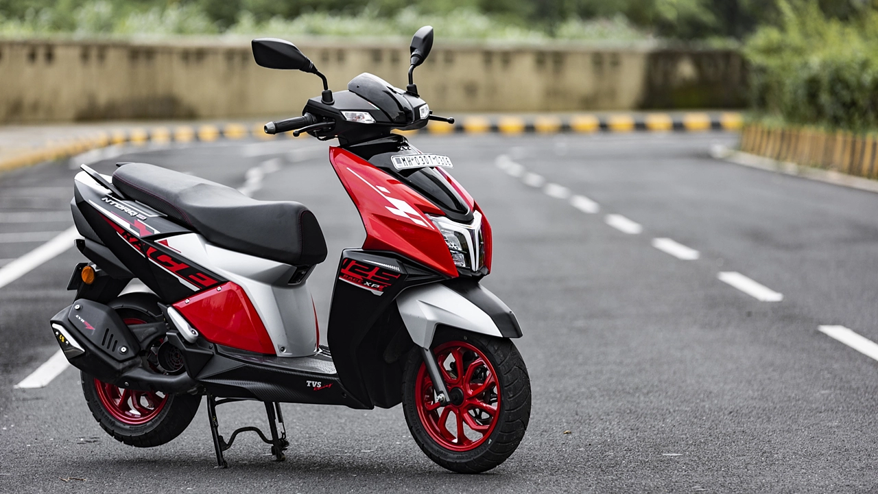 A parked red and black scooter on the road.
