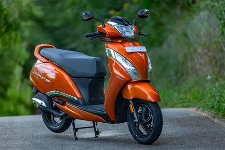 An orange scooter parked on the side of a road, ready for its next adventure.